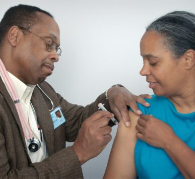 man doing syringe on woman wearing blue shirt